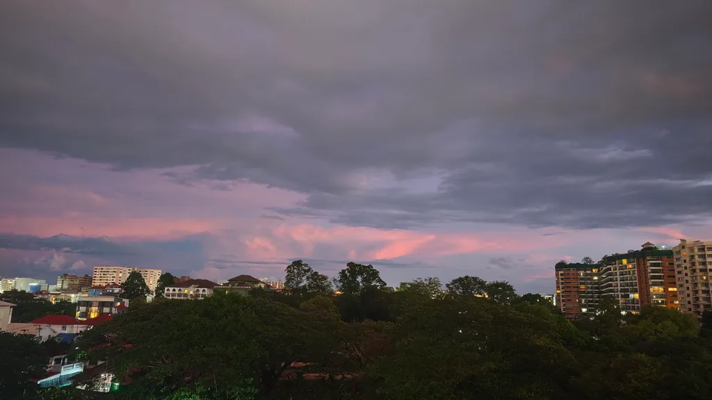 Abendhimmel mit dunklen Wolken über Bäumen und Hochhäusern