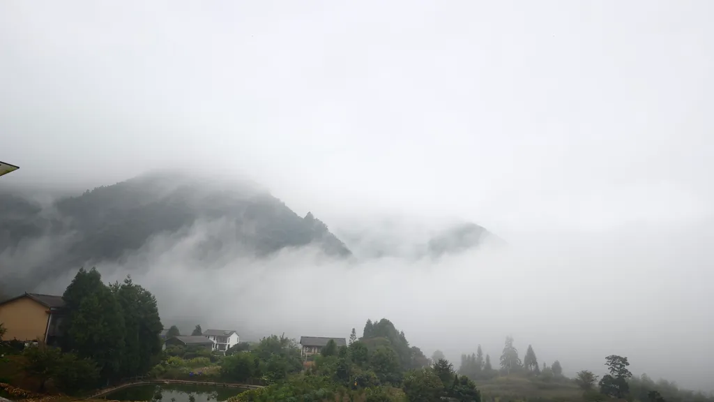 Nebel zieht über Berge und ein Dorf