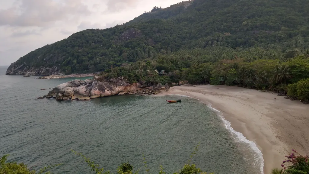 Bucht mit hellem Sandstrand und bewaldetem Hang