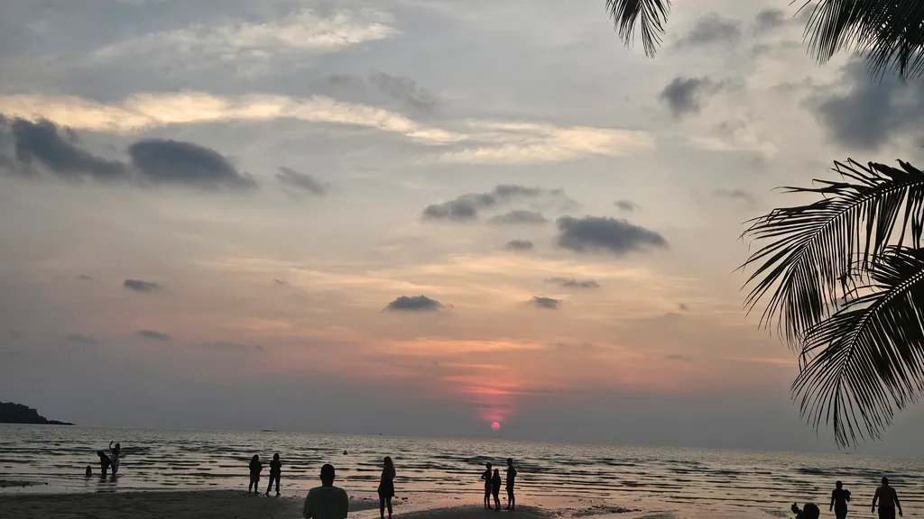 Strand bei Sonnenuntergang, Menschen als Silhouetten